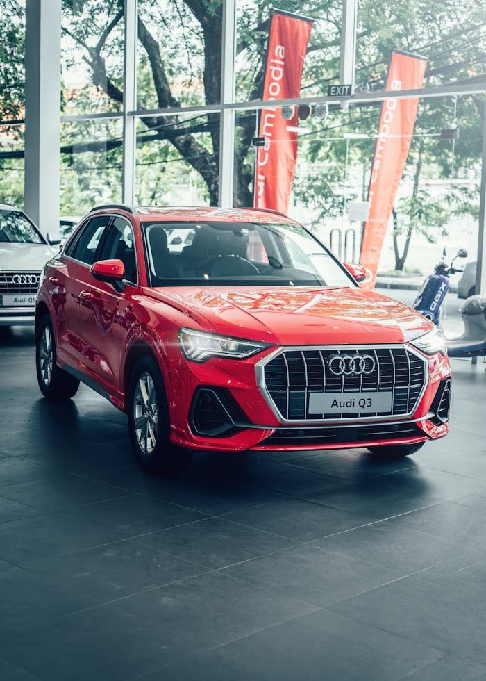 Bright red Audi Q3 displayed in a modern car showroom with promotional banners.